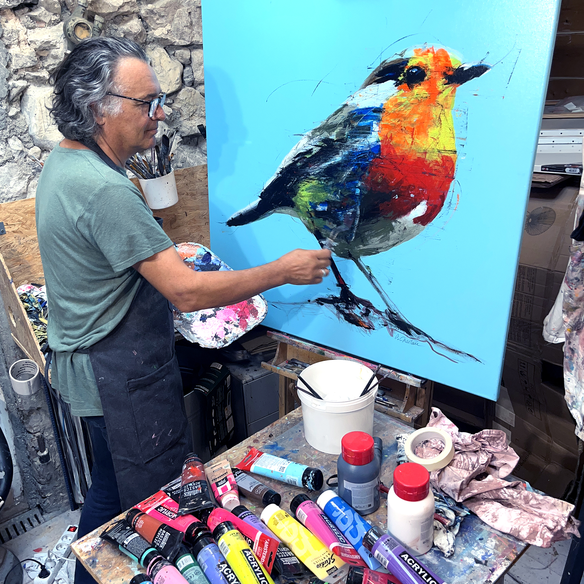 Didier Chastan artiste peintre à Grenoble réalisant une peinture d’oiseau coloré
